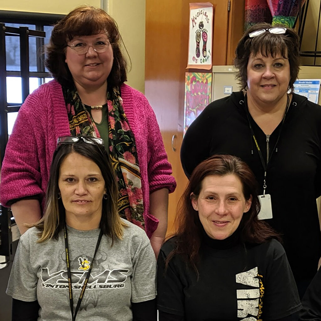 Four members of the Vinton-Shellsburg School Dsitrict staff seated in a classroom.