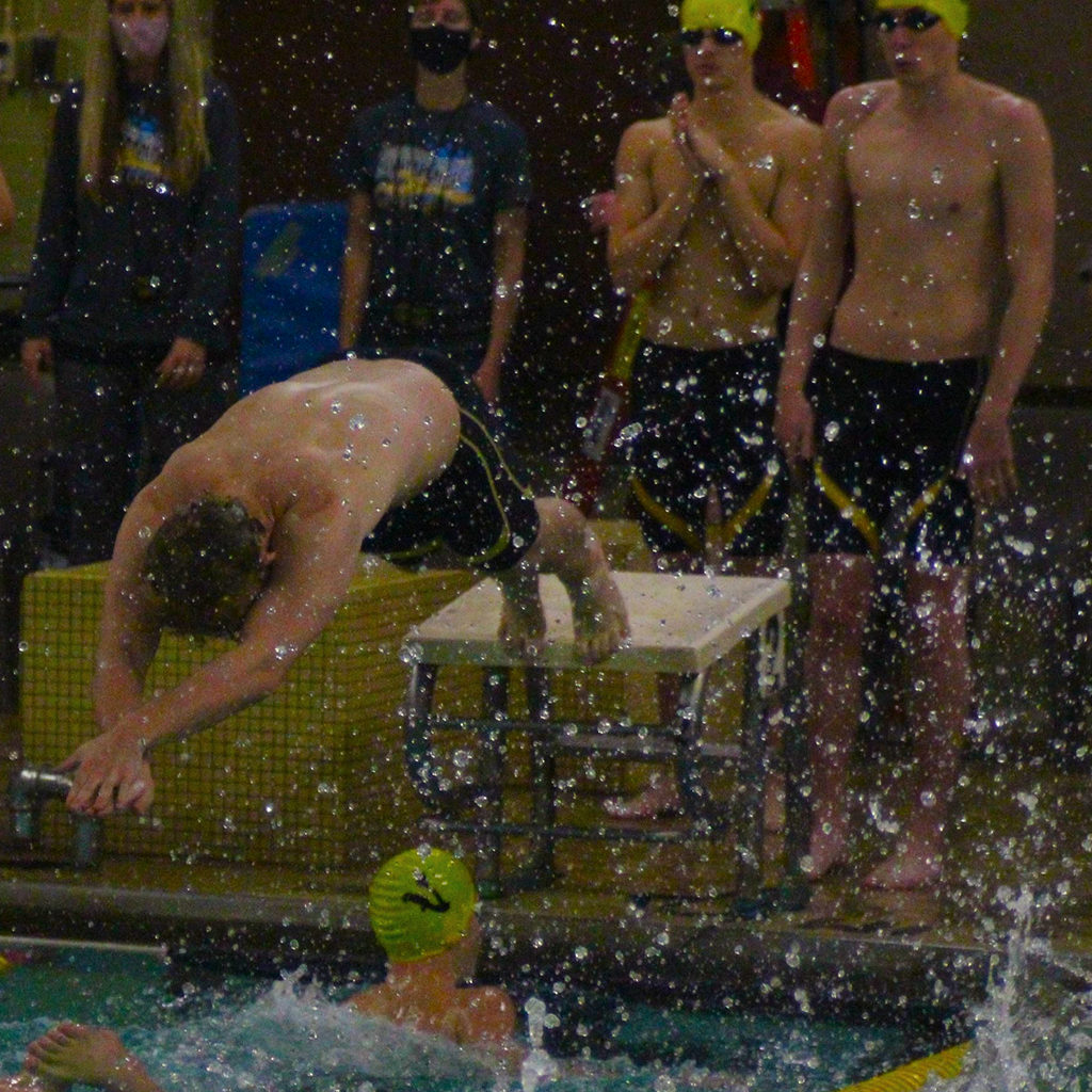 A swimmer dives of a platform to start a relay race.